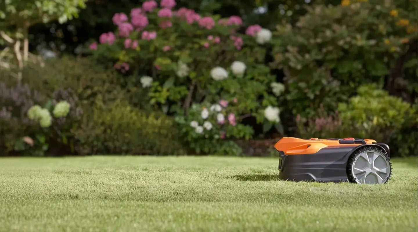 LawnMaster -robotmaaier op een groen gazon met bloeiende struiken op de achtergrond